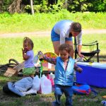 While the parents pack for the day, the children eat fruit. Serisa plays with the Braggs. While the parents pack for the day, the children eat fruit. Serisa plays with the Braggs.